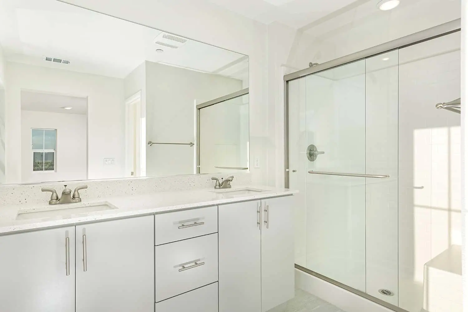 A bathroom with white cabinets and a large mirror.