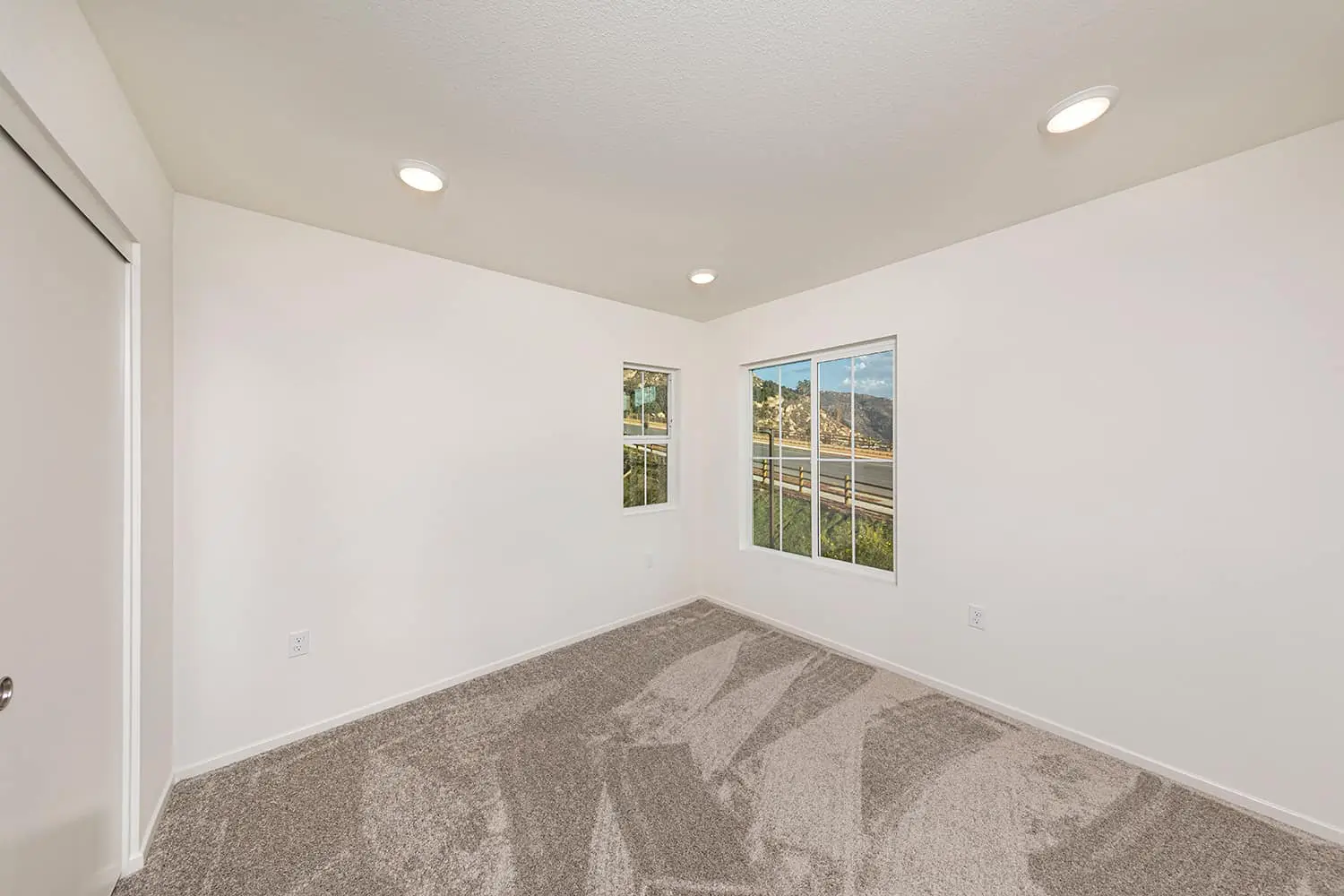 A room with a carpet and two windows.