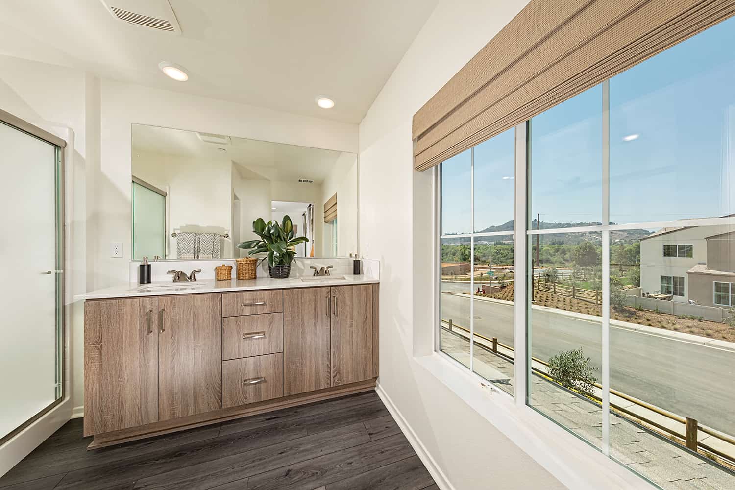 A bathroom with a large window and wooden cabinets.