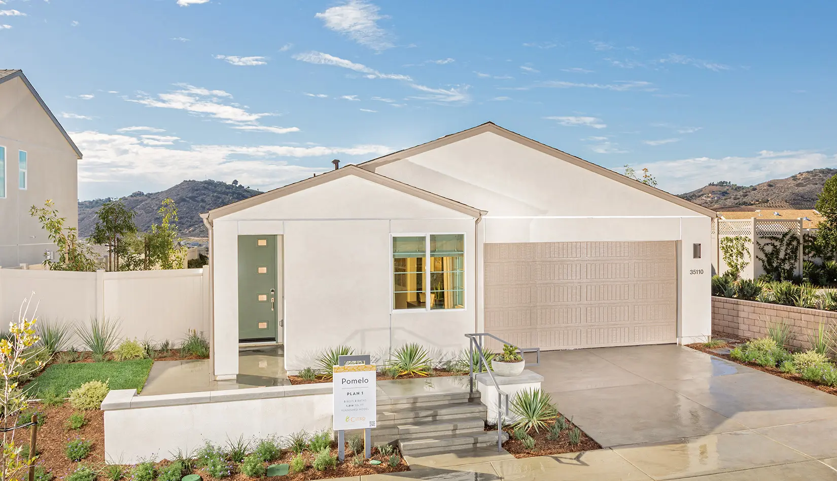 A white house with a garage and steps leading to it.