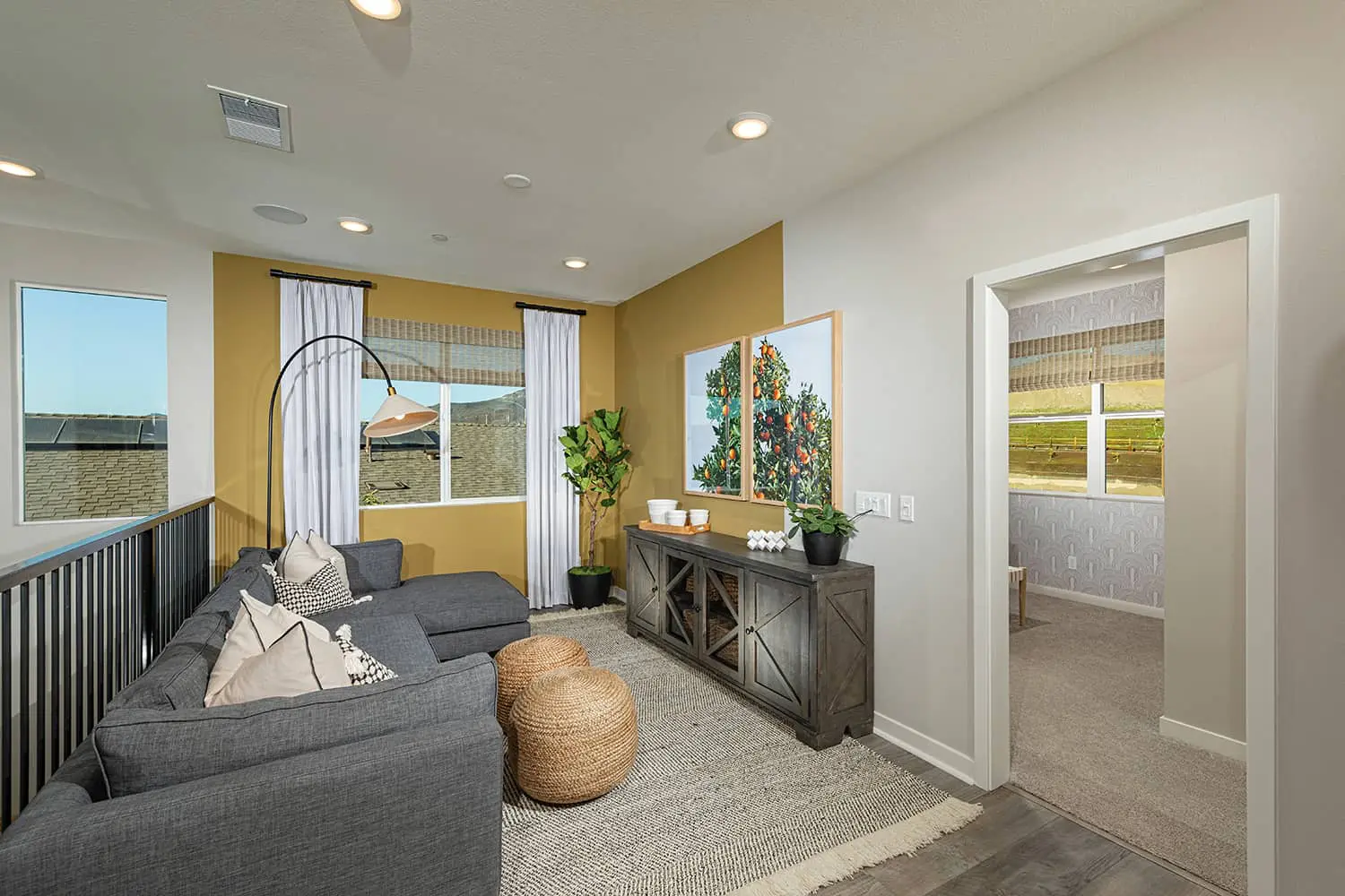 A living room with yellow walls and gray furniture.