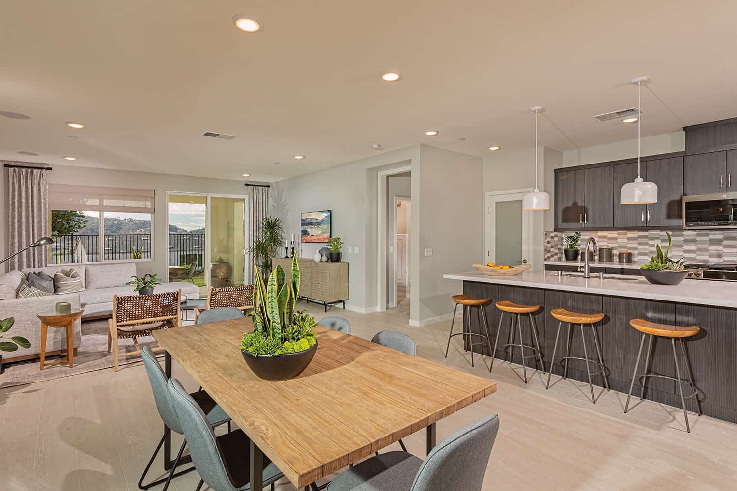 A dining room table with chairs and a bar in the background.