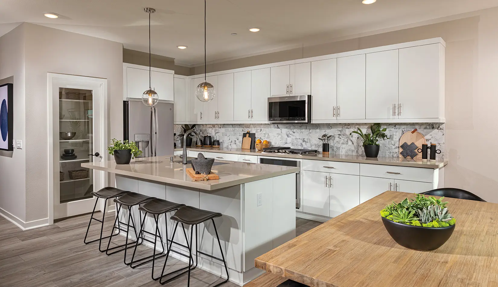 A kitchen with white cabinets and black stools.