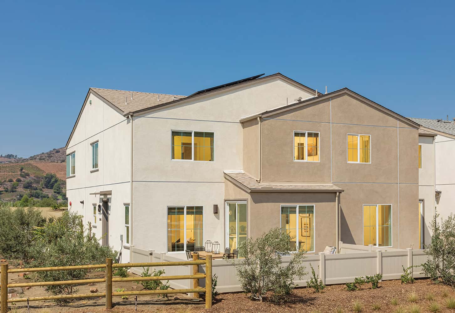 A white house with two windows and a fence.