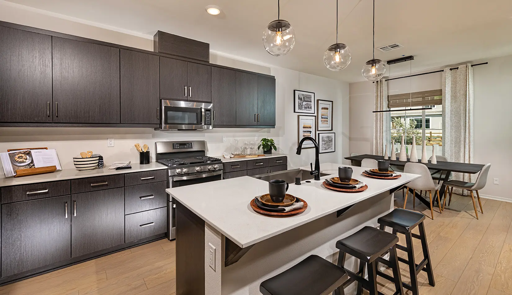 A kitchen with dark cabinets and white counters.