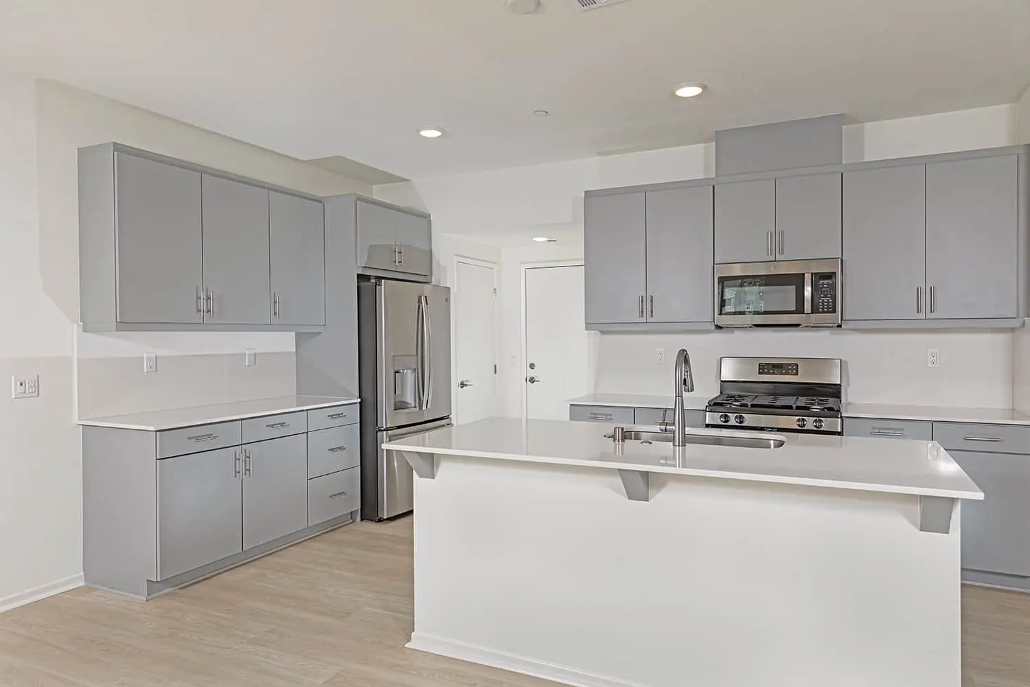 A kitchen with grey cabinets and white walls.