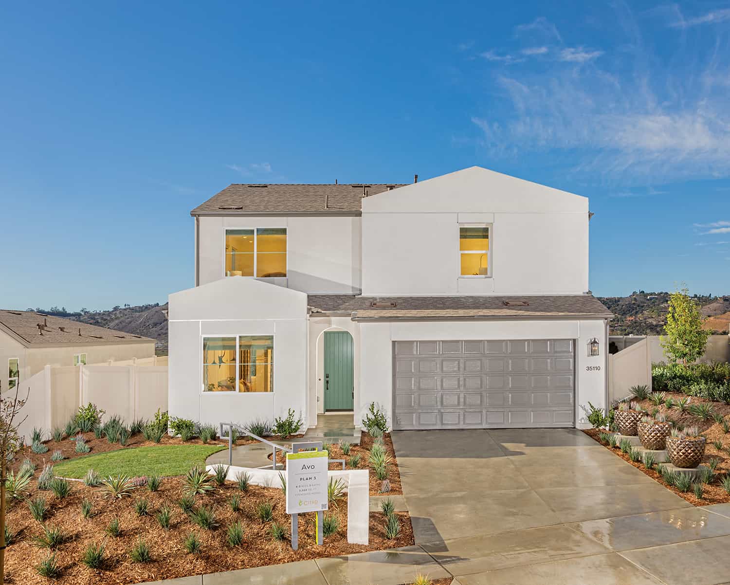 A white house with a driveway and landscaping.