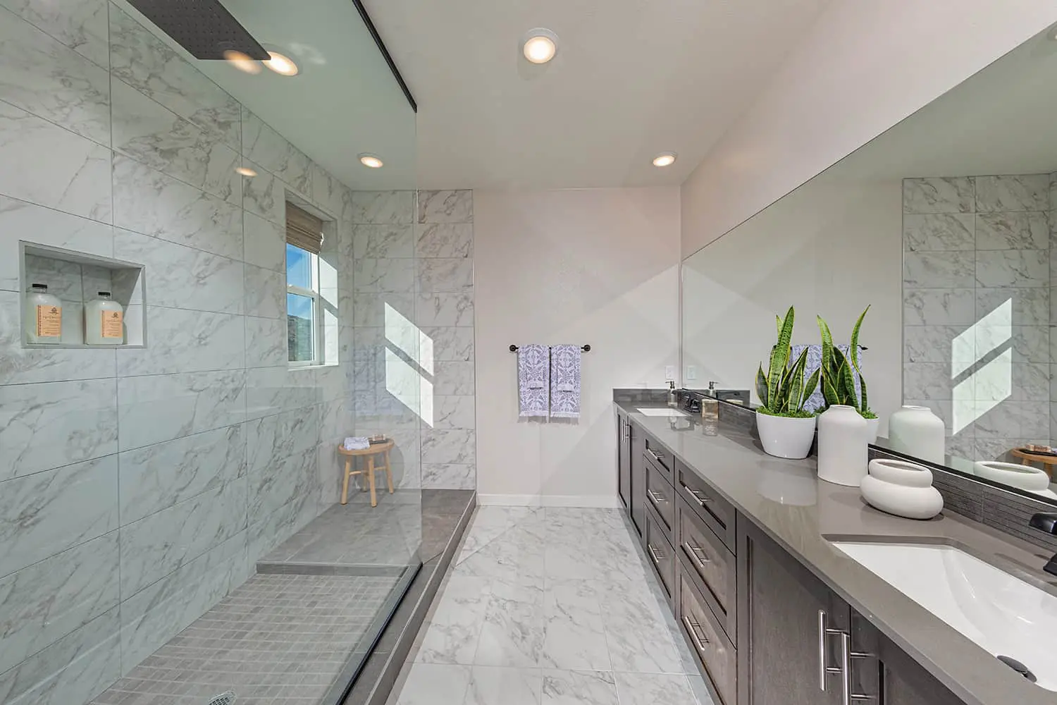 A bathroom with marble walls and floors, and a large mirror.