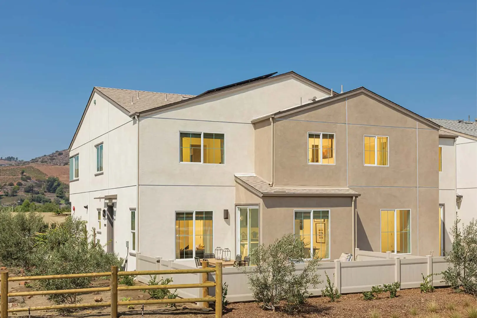 A white and beige house with yellow windows.